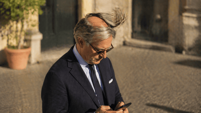 Uomo con riporto capelli in strada: il vento solleva i capelli rivelando la calvizie