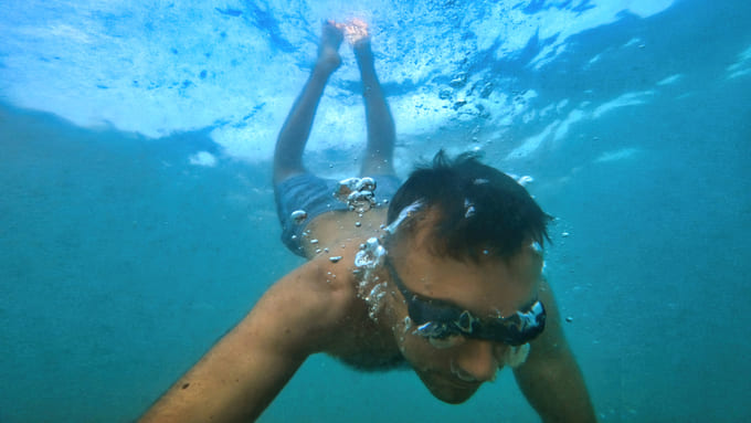 Uomo che nuota sott'acqua con maschera da snorkeling